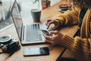 Someone using a laptop, holding a credit card and making an online purchase.