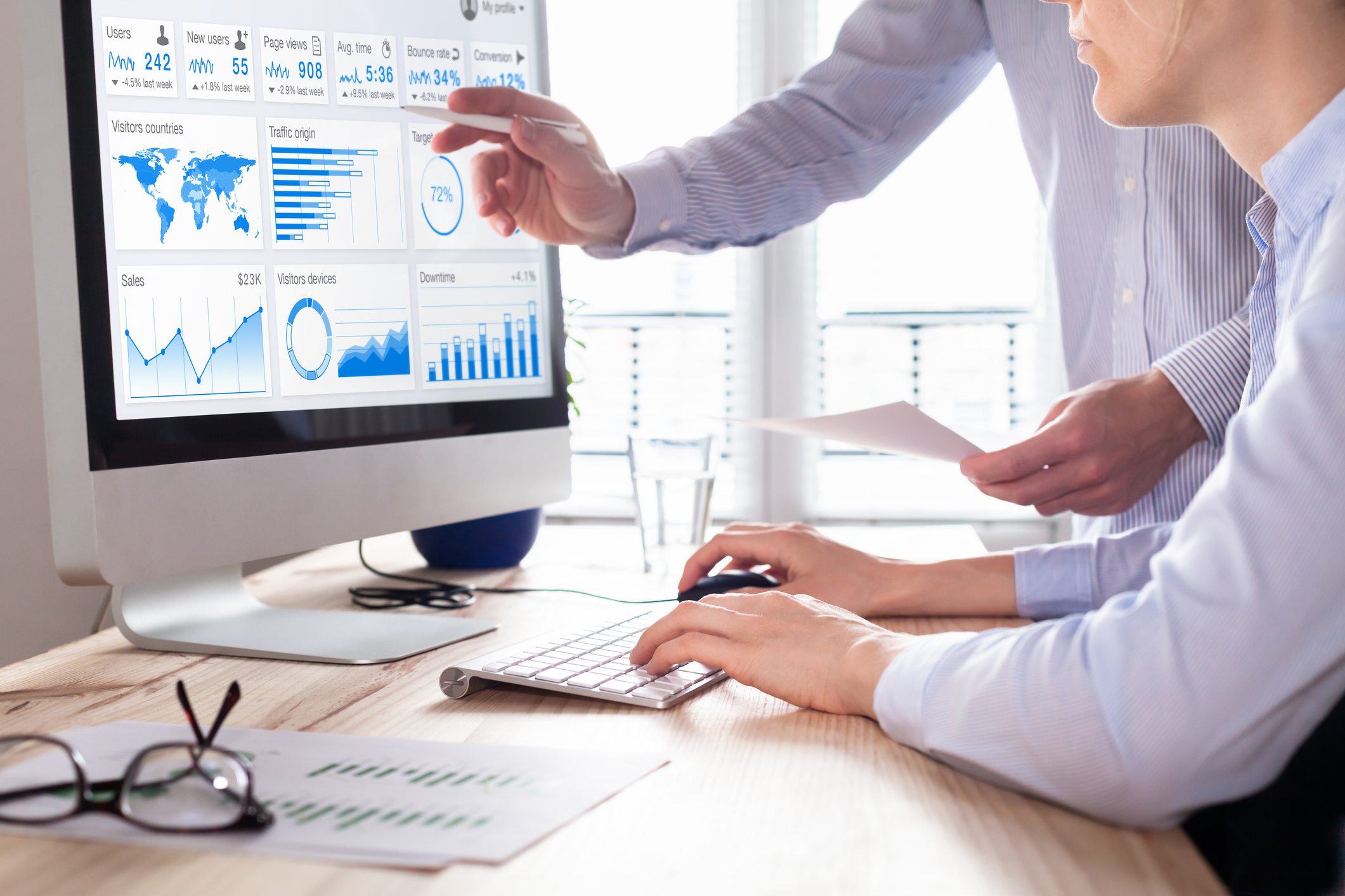 Team of business people discussing digital marketing metrics report for advertisement campaign, data analytics dashboard on computer screen in office.