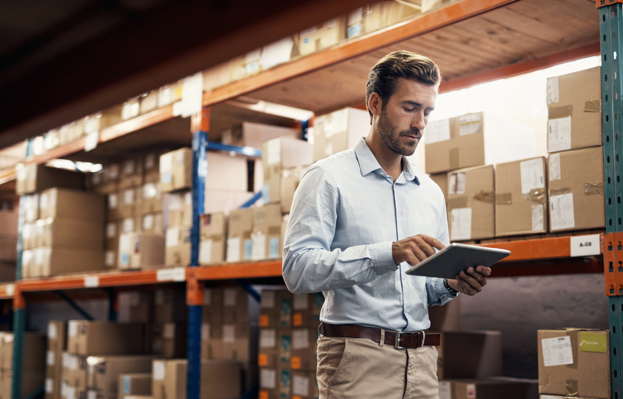Shot of a young man using a digital tablet while working in a fulfilment warehouse checking inventory.