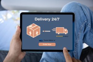 Man hands hold computer tablet with parcel delivery application over table in office