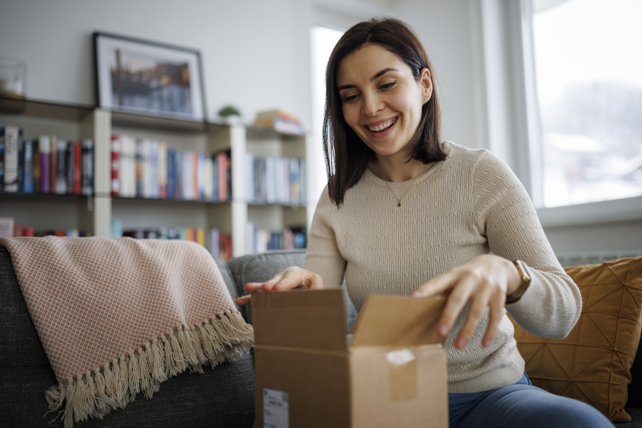 Excited young woman unpacking her latest online delivery at home